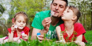 Padre con niñas soplando burbujas